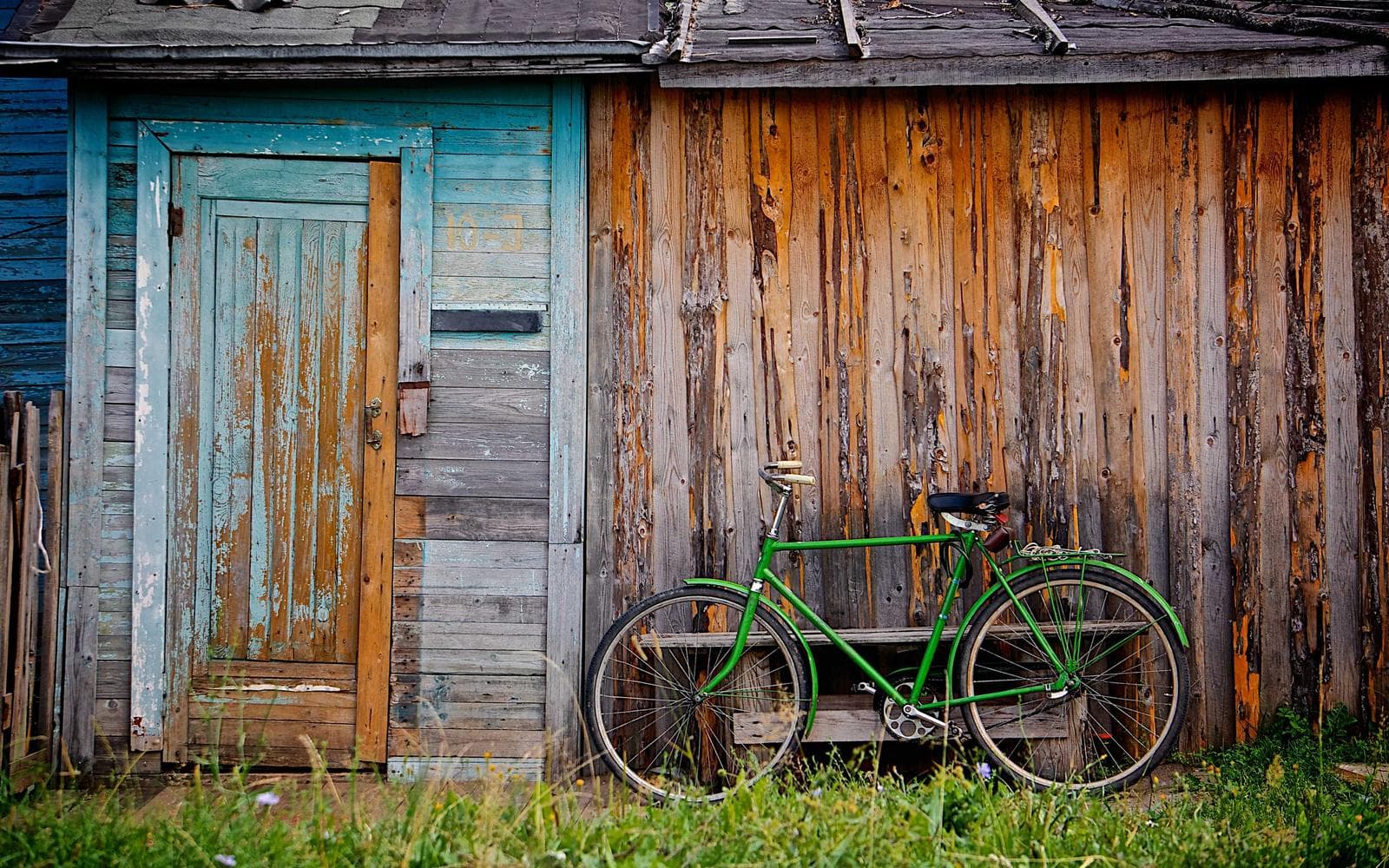 A weathered wooden door with a bicycle leaning on it